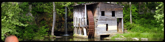 Image of an old water mill sitting beside a small waterfall